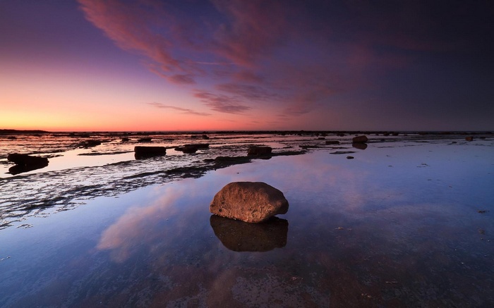 Rocky shore at sunset with colorful sky reflection