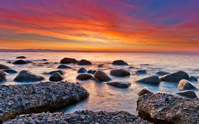 Rocky shoreline at sunset with colorful sky