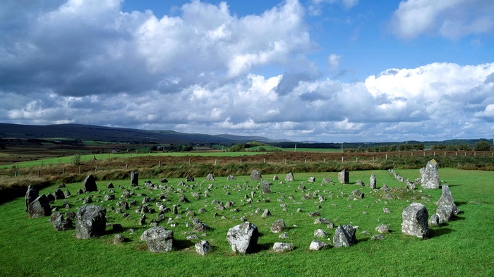 Standing stones in a grassy field under a cloudy sky