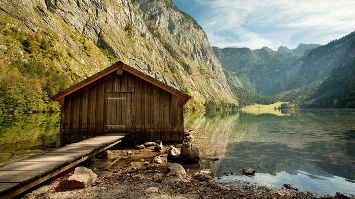 Wooden boathouse on a calm lake with mountains