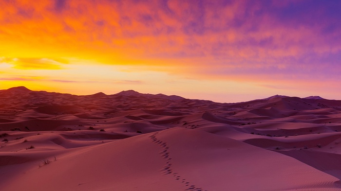 Desert dunes at sunset with colorful sky