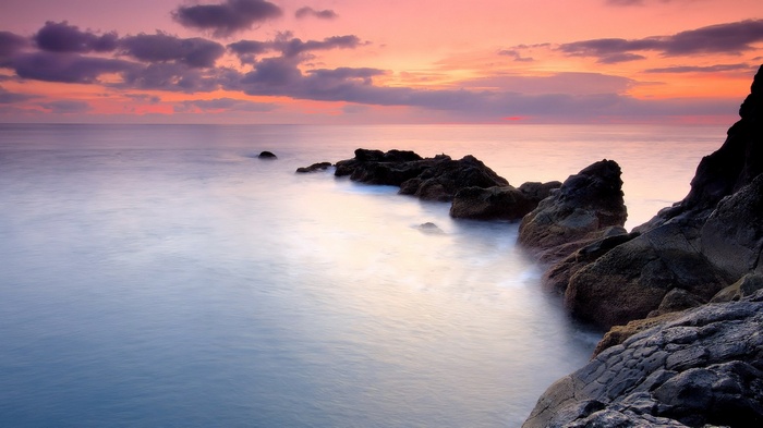 Rocky coastline at sunset with calm ocean