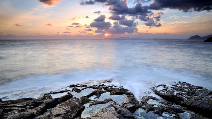 Sunset over the ocean with rocky shore