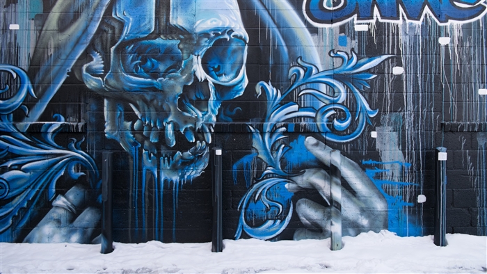Graffiti skull with blue ornate details on brick wall