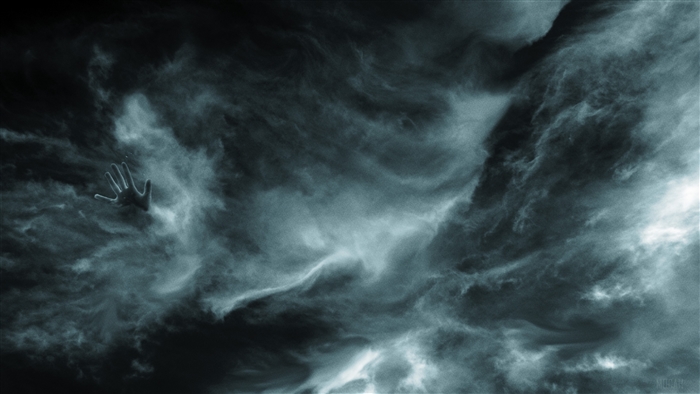 Hand reaching through dark clouds