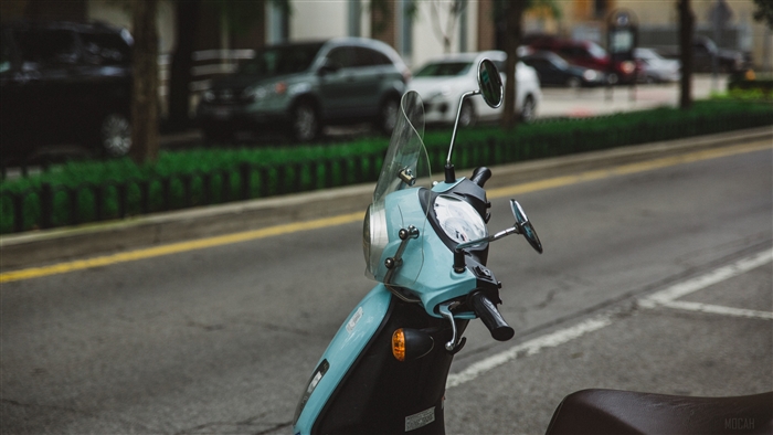 Light blue scooter with windshield on a street