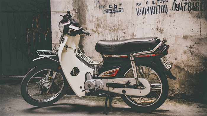 Honda Dream II motorcycle parked against a textured wall