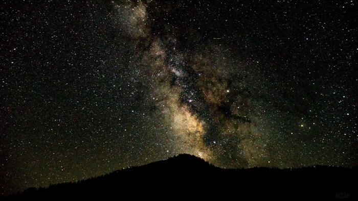 Starry night sky with the Milky Way over a silhouetted mountain