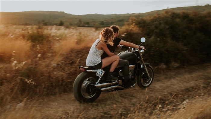 Couple riding a motorcycle in a field
