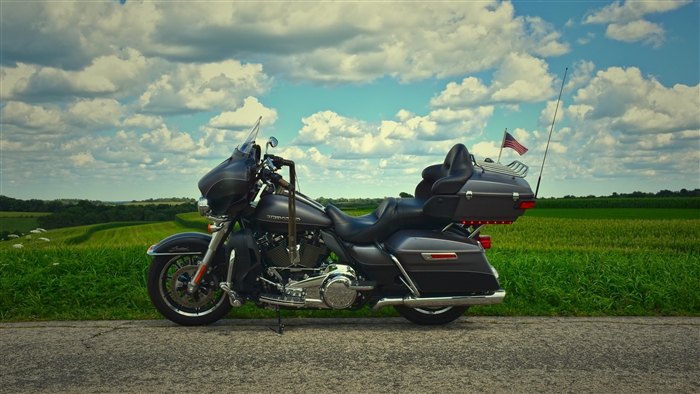 Harley-Davidson motorcycle parked on a road with fields and clouds