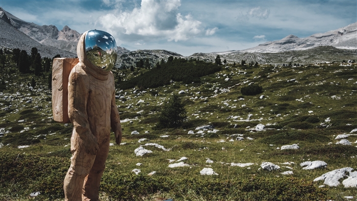 Wooden cosmonaut sculpture in a mountain landscape 4K
