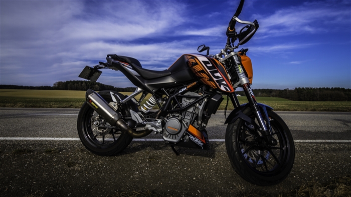 KTM motorcycle on a road with fields and sky