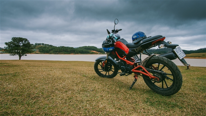 Motorcycle parked on grass by a lake