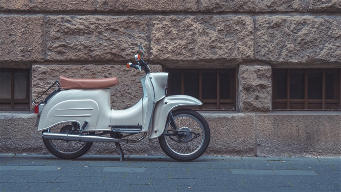 White scooter parked against a stone wall