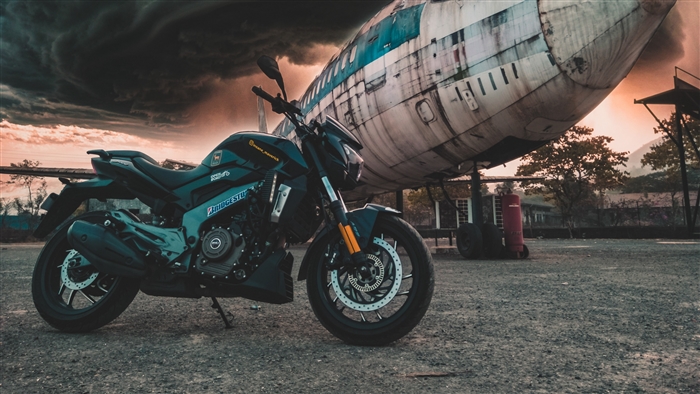 Motorcycle parked in front of an airplane under stormy clouds