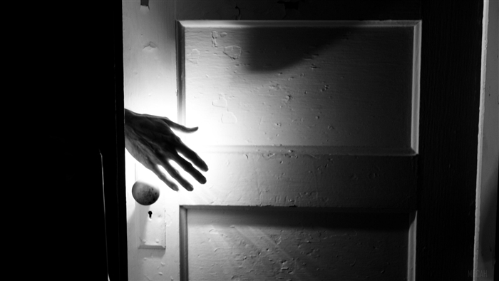 Hand reaching through a dark doorway