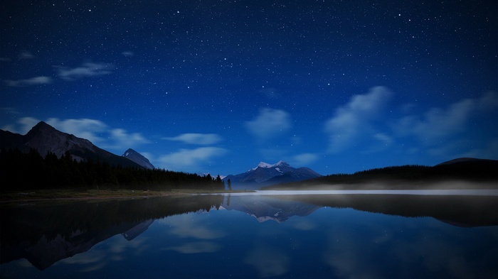 Night sky over a misty lake and mountains