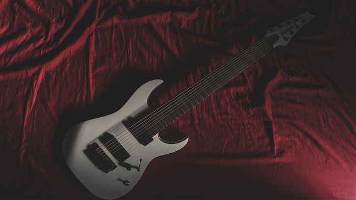 White 8-string electric guitar on red fabric