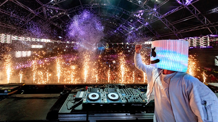 Marshmello performing at a concert with fireworks