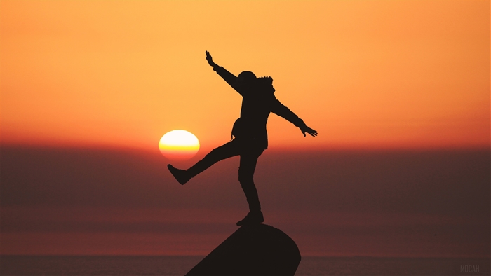 Silhouette of a person balancing at sunset
