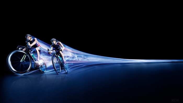 Two triathletes cycling with light trails