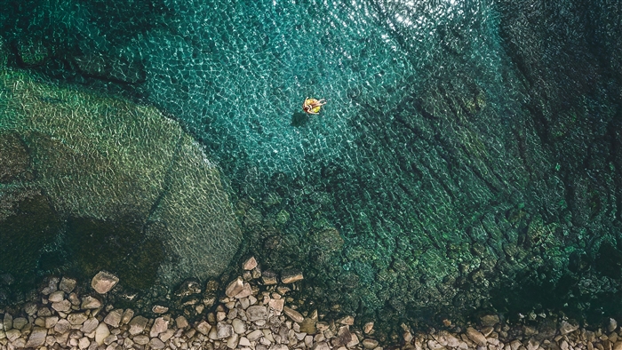Person on inflatable in clear turquoise water