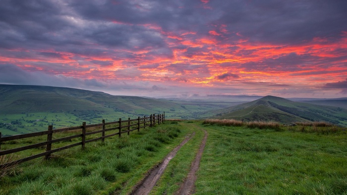 Rolling green hills at sunset with a dirt path