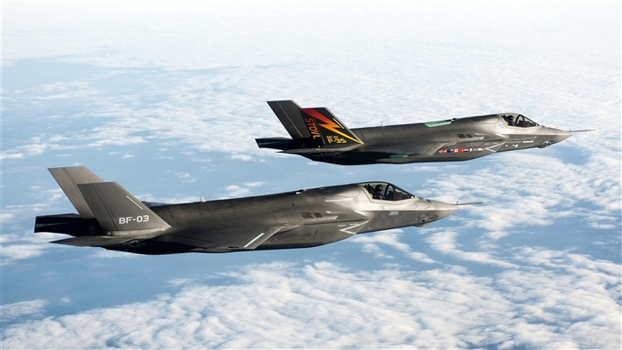 Two F-35 fighter jets flying above clouds