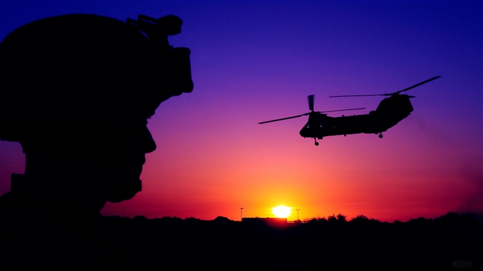 Silhouette of soldier watching CH-46 Sea Knight helicopter at sunset