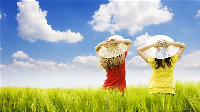 Two girls in hats in a field