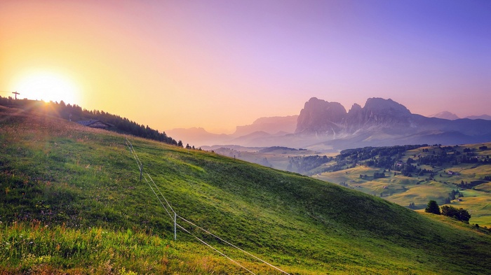 Sunrise over a green mountain landscape with distant peaks