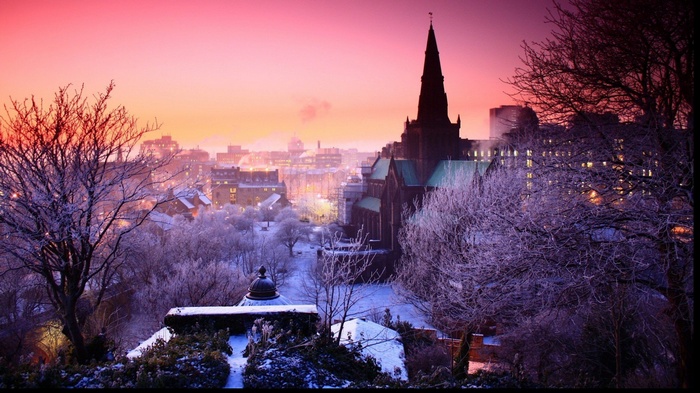Snowy city skyline at sunset with church