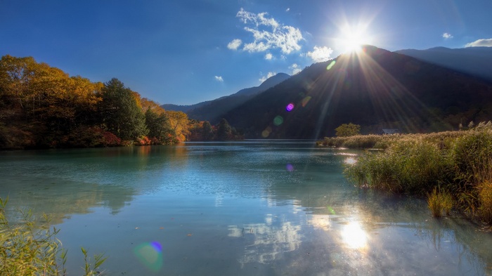 Lake and mountains during autumn with sun flare