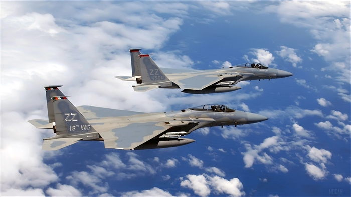 Two F-15C Eagles fly over clouds
