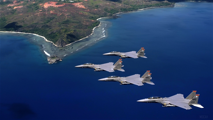 F-15E Strike Eagles flying over ocean near island