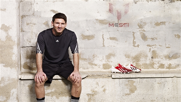 Lionel Messi sitting with Adidas shoes