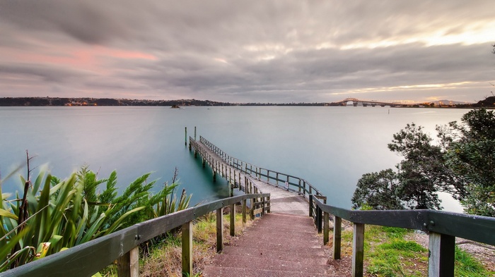 Wooden pier extending into a calm bay at sunset