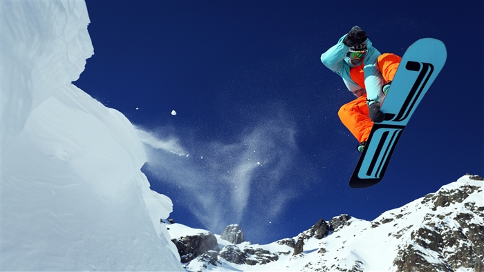 Snowboarder jumping off a snowy mountain cliff in 4K