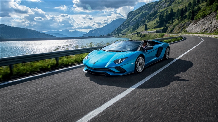 Blue Lamborghini Aventador S Roadster driving on mountain road
