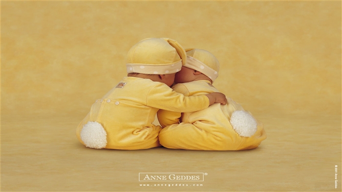 Two babies in yellow bunny outfits hugging