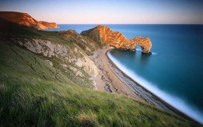 Durdle Door rock arch on a beach at sunset