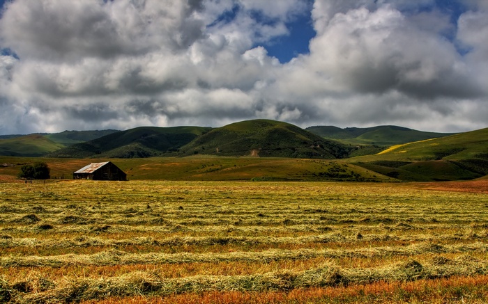 Barn in a field with rolling hills and clouds