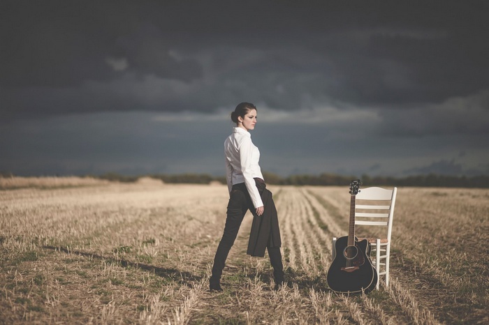 Woman in white shirt with guitar in field