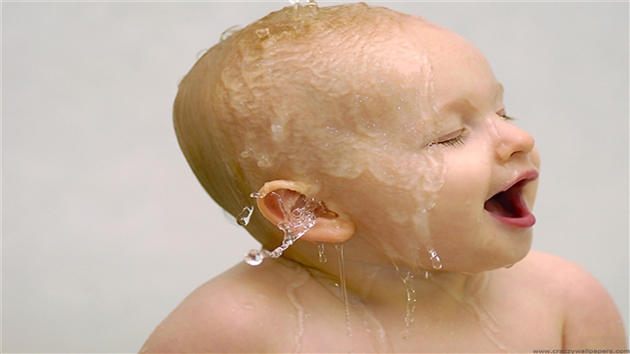 Cute baby getting water poured on head