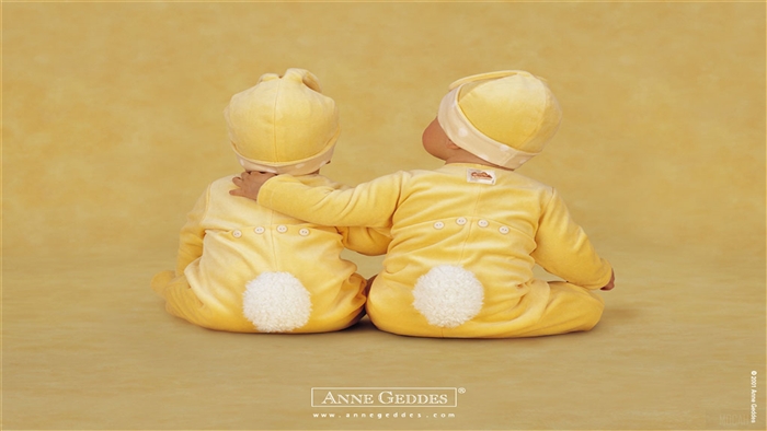 Two babies in yellow bunny outfits with Anne Geddes logo
