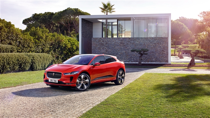 Red Jaguar I-PACE EV400 HSE parked in front of modern house