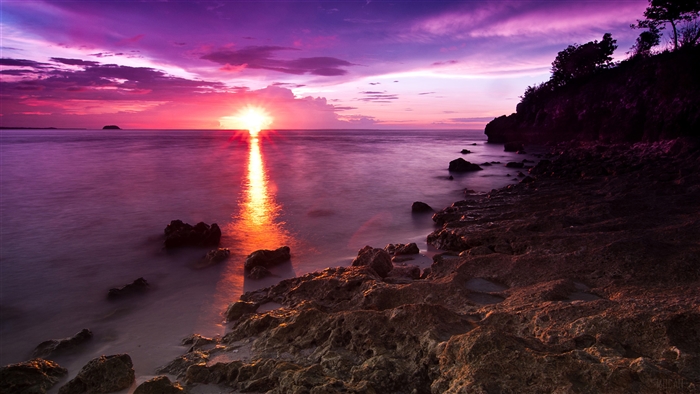 Sunset over the ocean with rocky shore