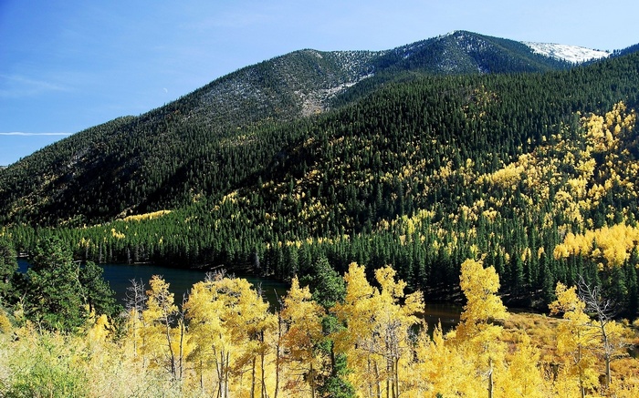 Mountain lake surrounded by evergreen and aspen trees in autumn