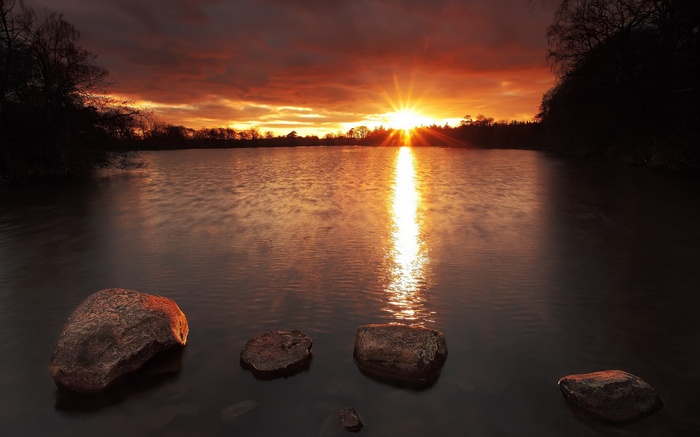 Sunset over a lake with rocks in the foreground