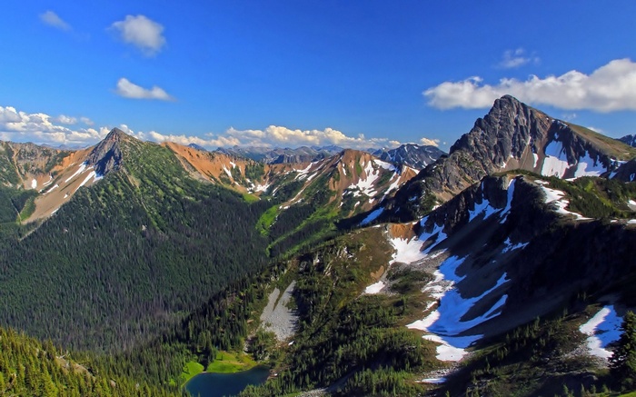 Mountain range with snow patches and a lake